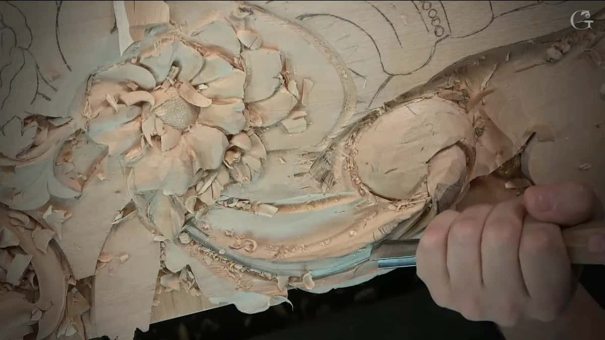 A long gouge pass running along the curved section, right beside a carved flower with a punched centre