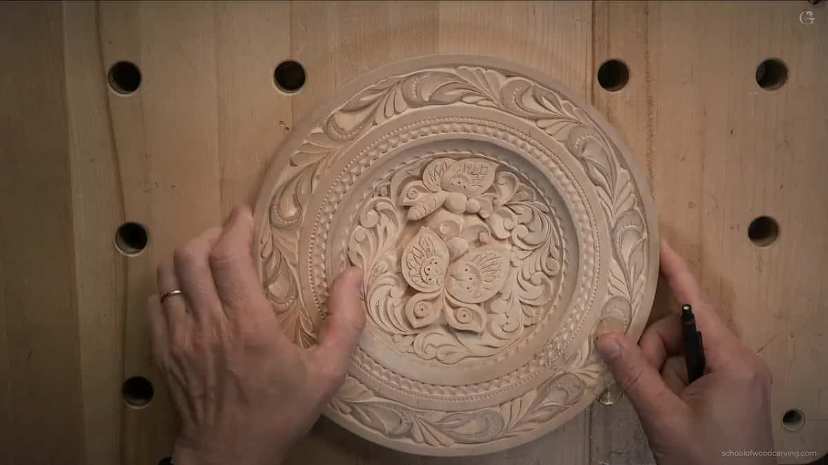 Both hands rest on the finished plate, one holding a black pen