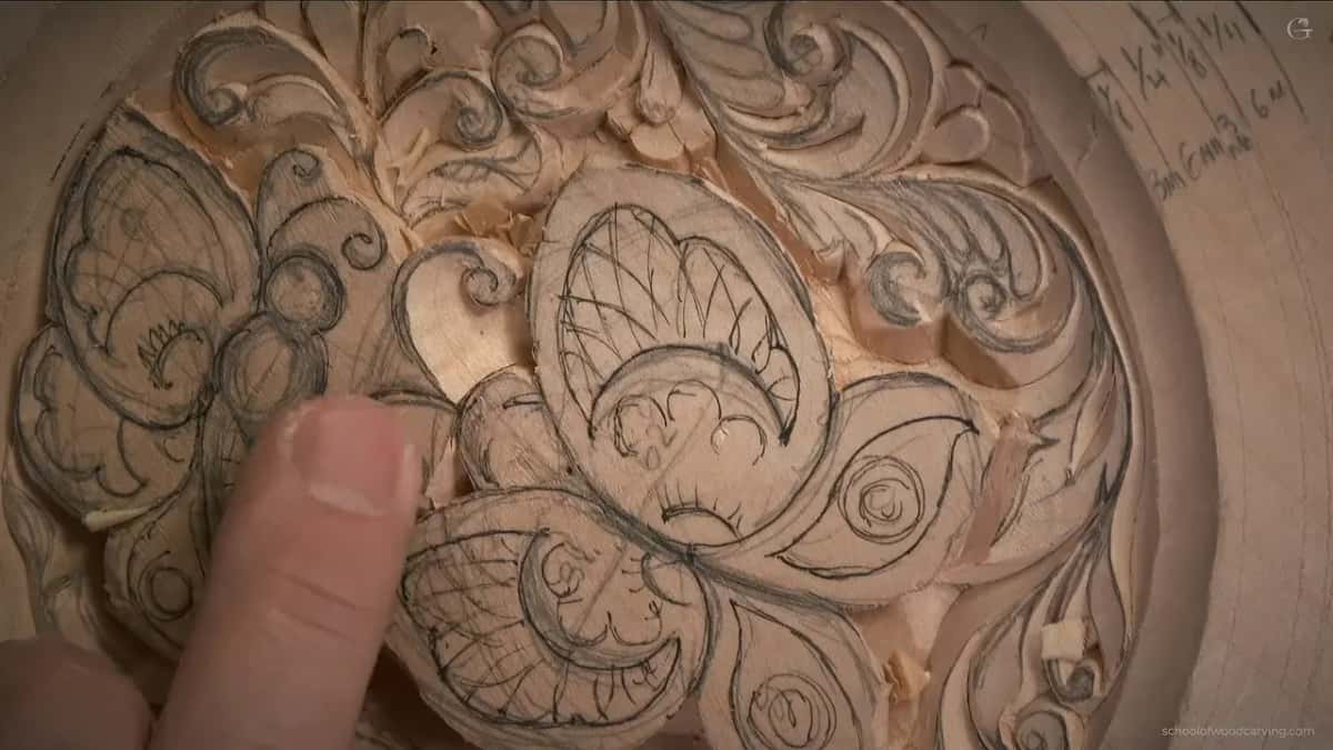Pencil lines still cover one butterfly, and a fingertip rests beside it near notes on the rim