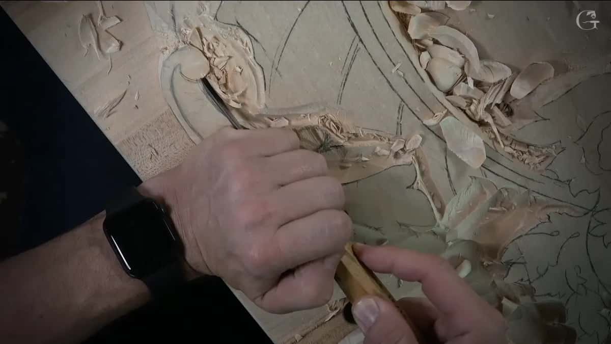 Two hands guiding a gouge round the volute