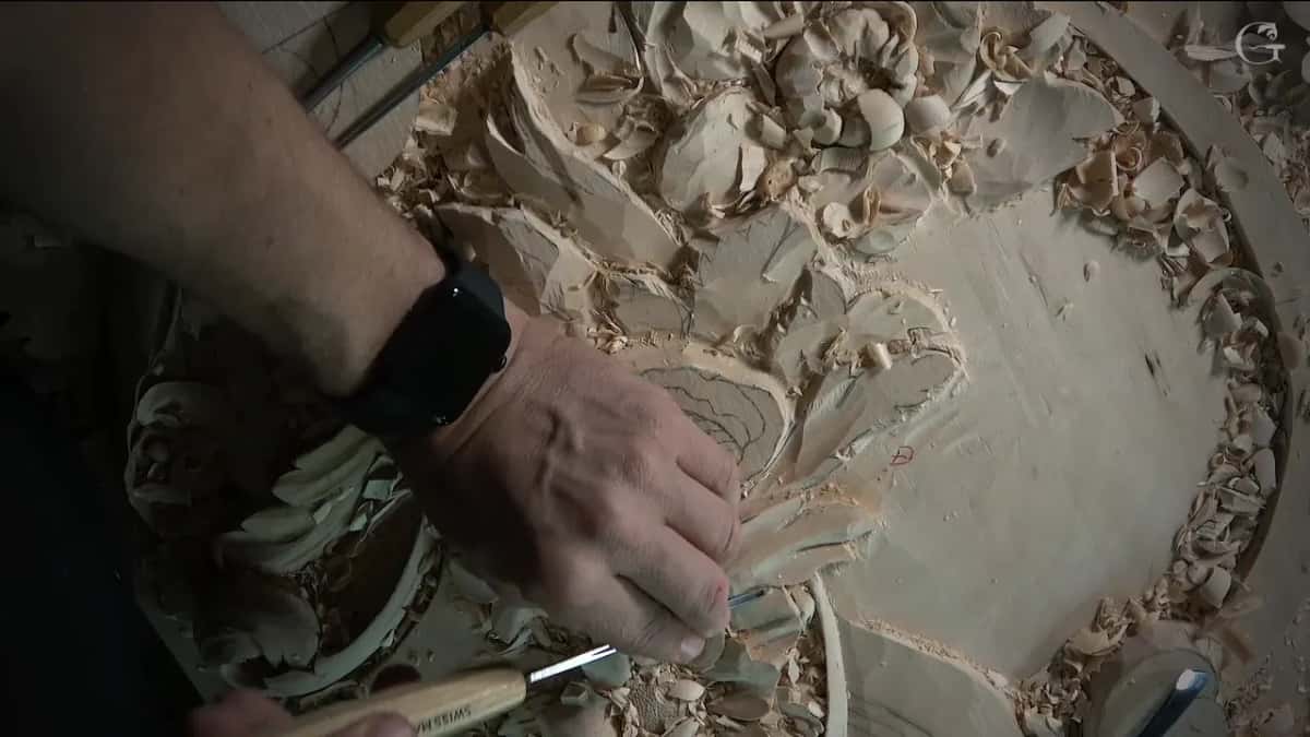 Hand working at a leaf tip while other tools lie near the edges