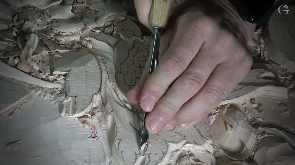 One hand holds a tool upright on the outline next to the gridded flower