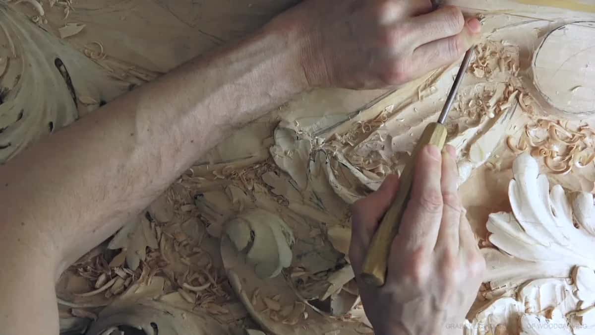 Held almost upright, a small gouge works at the edge of the molding.
