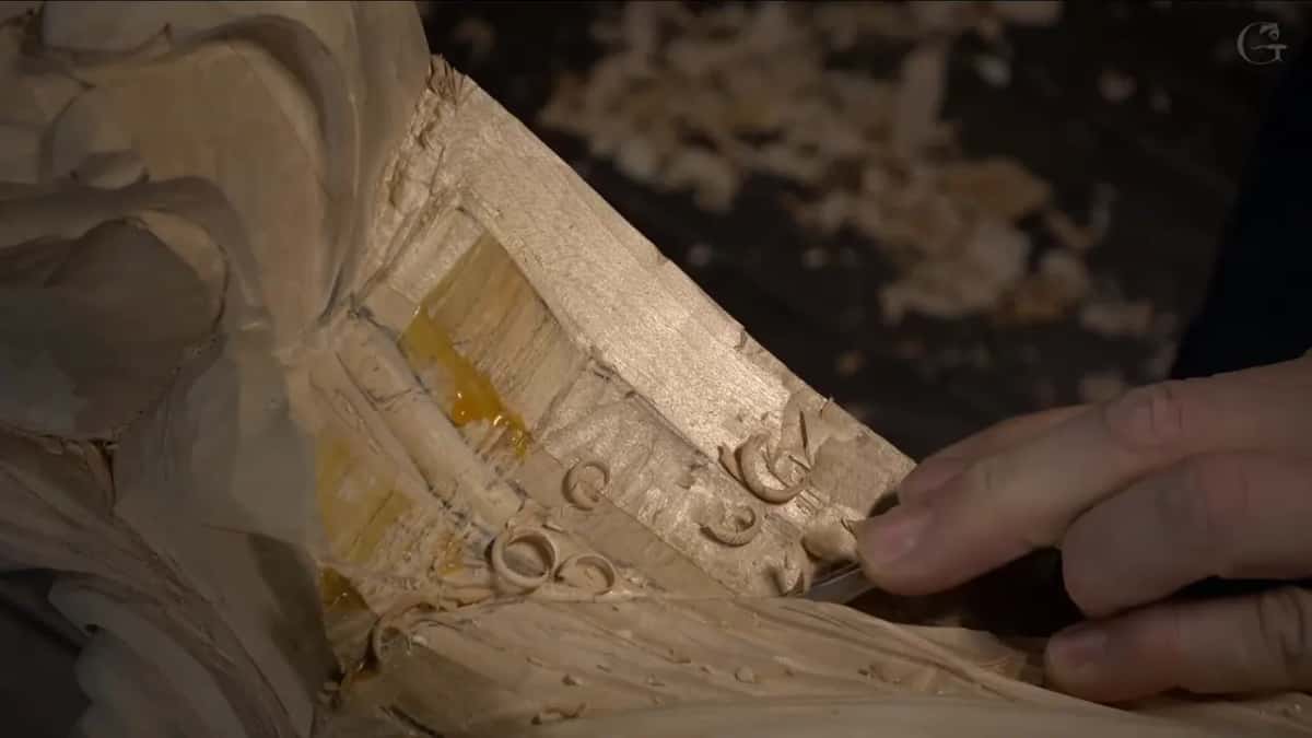 Curled shavings lift out of a narrow channel.