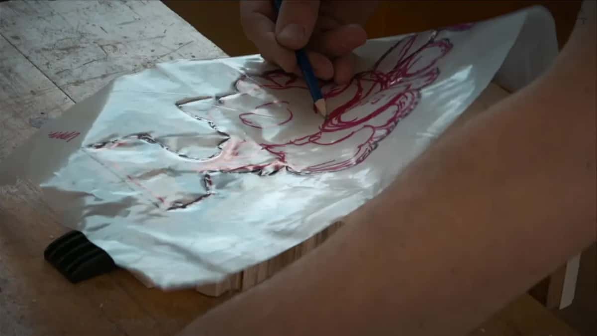Clear plastic sheet, the design on it in red marker, laid over the roughed blank