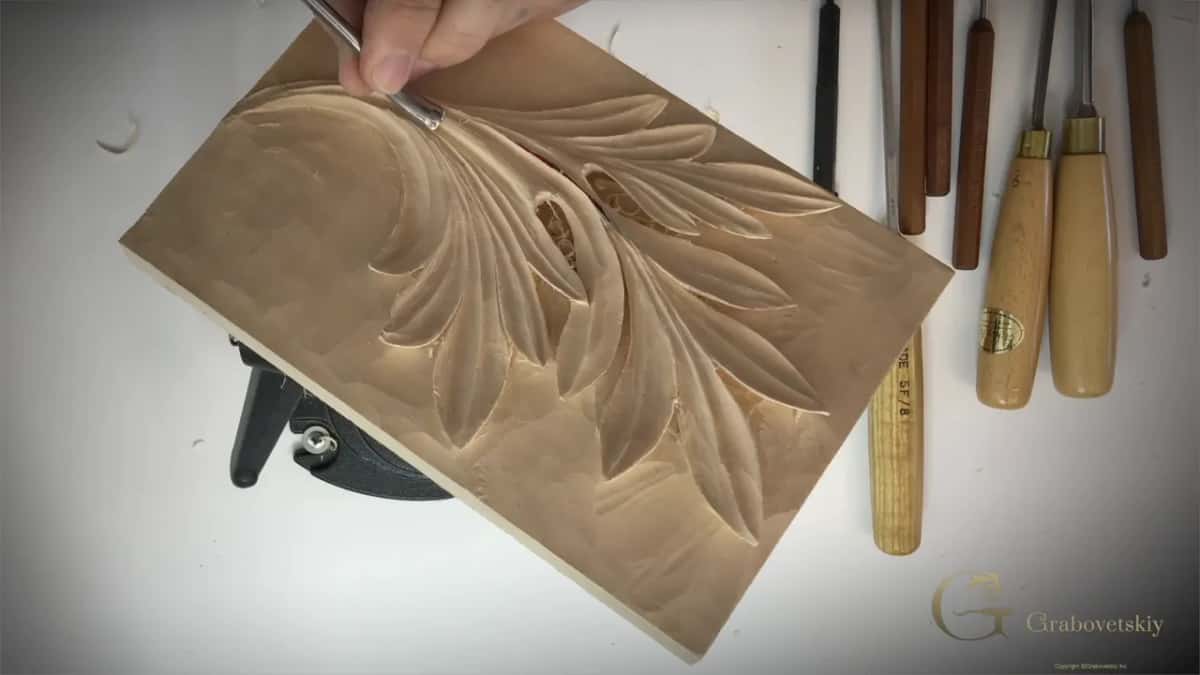The leaf at an angle with a fine tool at one eye, and a row of gouges along the right edge.