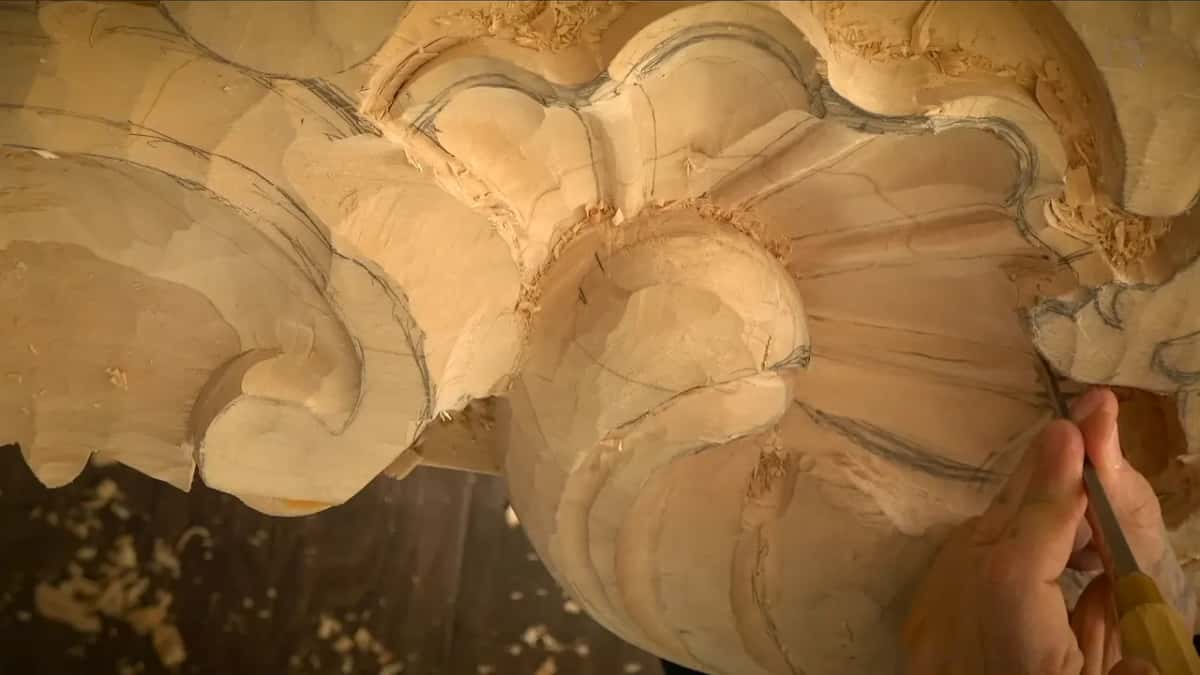 One hand guides a gouge along a pencil line.