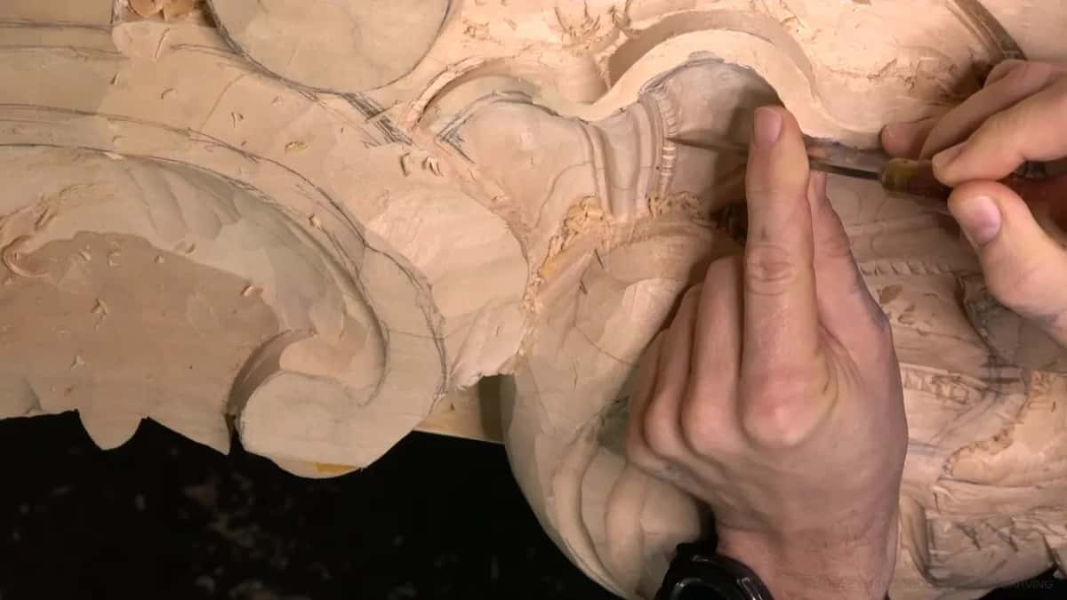 Two hands work a tiny tool into a tight gap in the row.