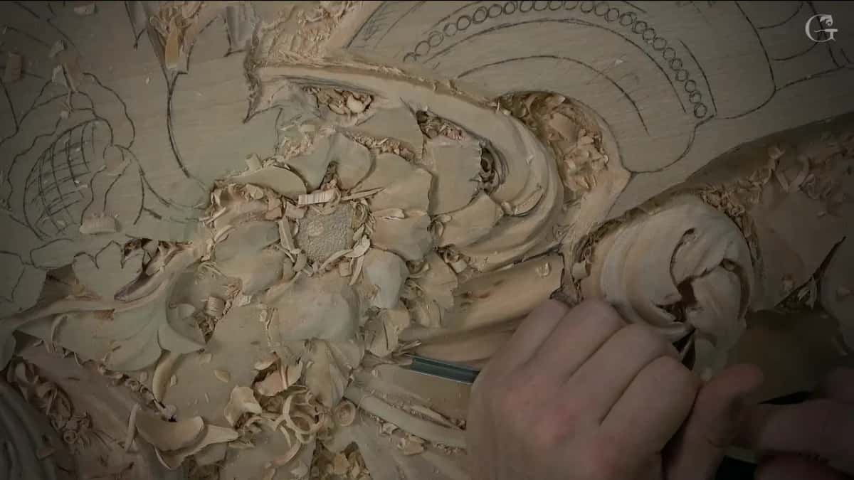 One hand and a thin tool beside the scroll