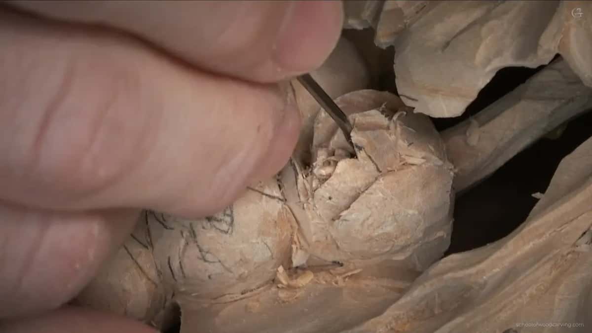Lines in pencil on the bud beside the one being carved, fingers close over a tiny tool