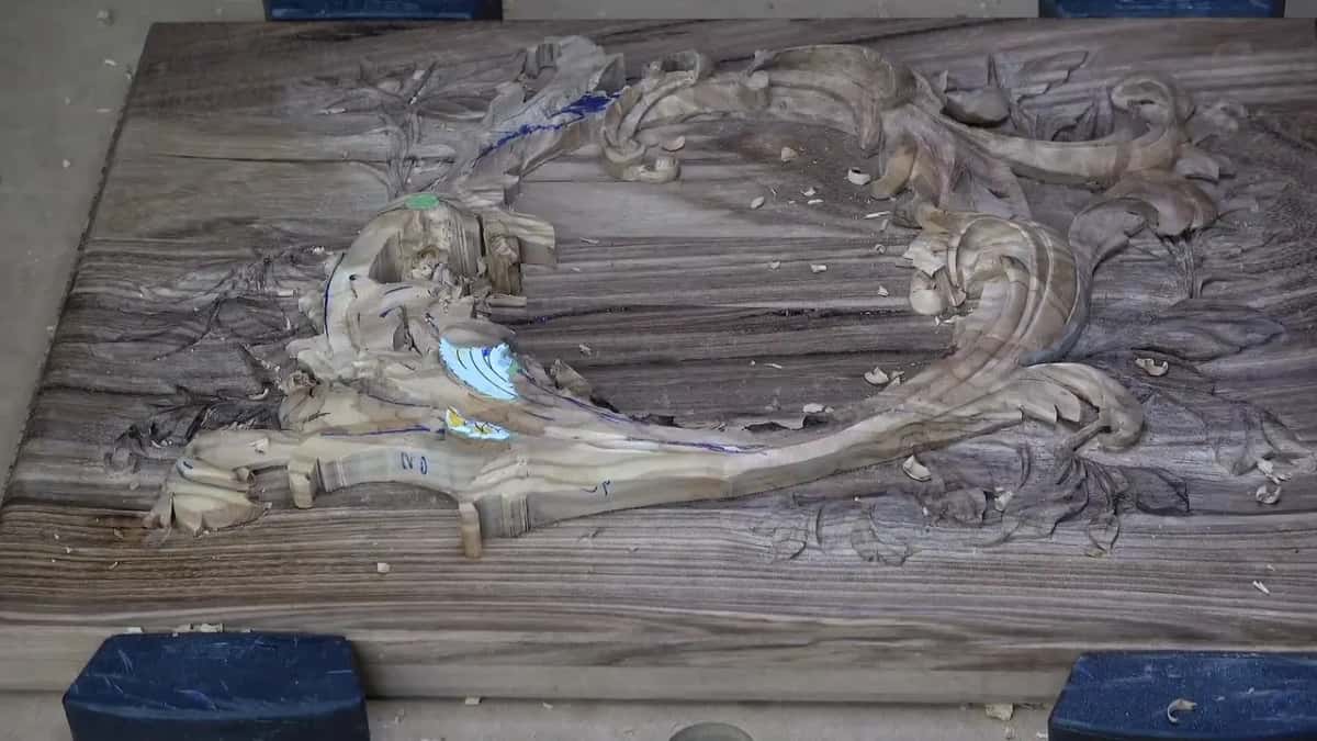 The whole lid on the bench, a pale olive layer curving over carved acacia, blue blocks at each corner