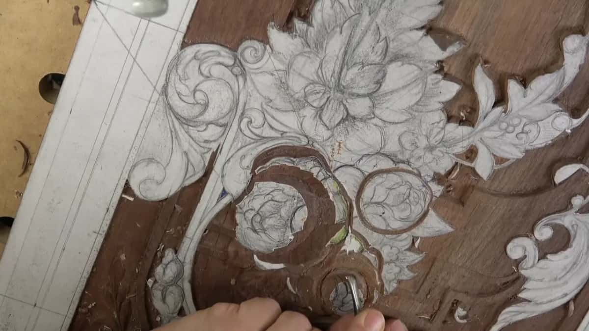 Fingers low in the frame, a small tool at the base of the round bloom
