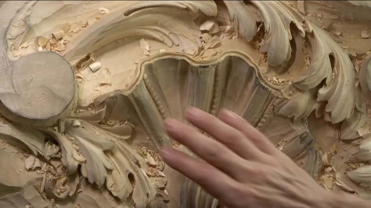 An open hand beside the shell, its thin rim standing just above a dark groove.
