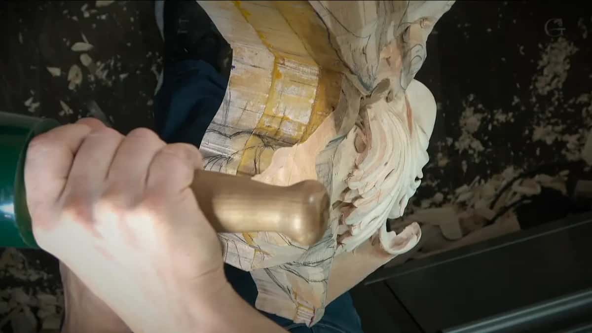 A fist around a green mallet above the carved scrolls