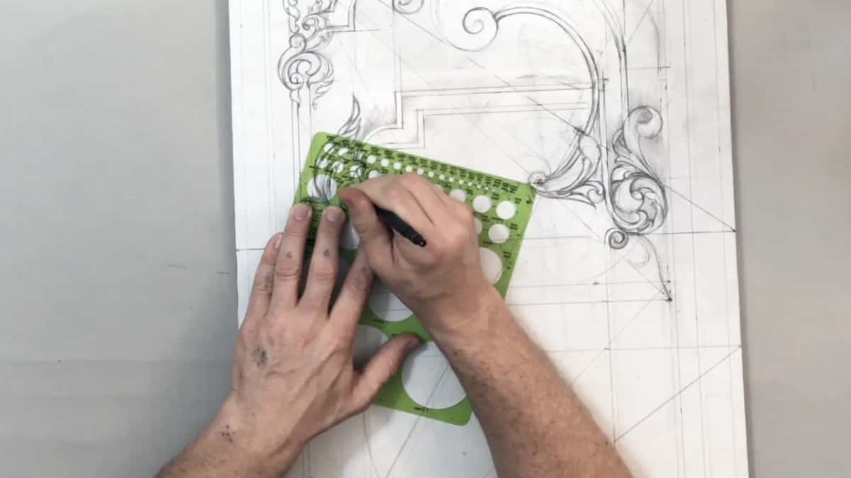 Green circle template held down on the sheet while a pencil runs round one of its holes to true a sweep