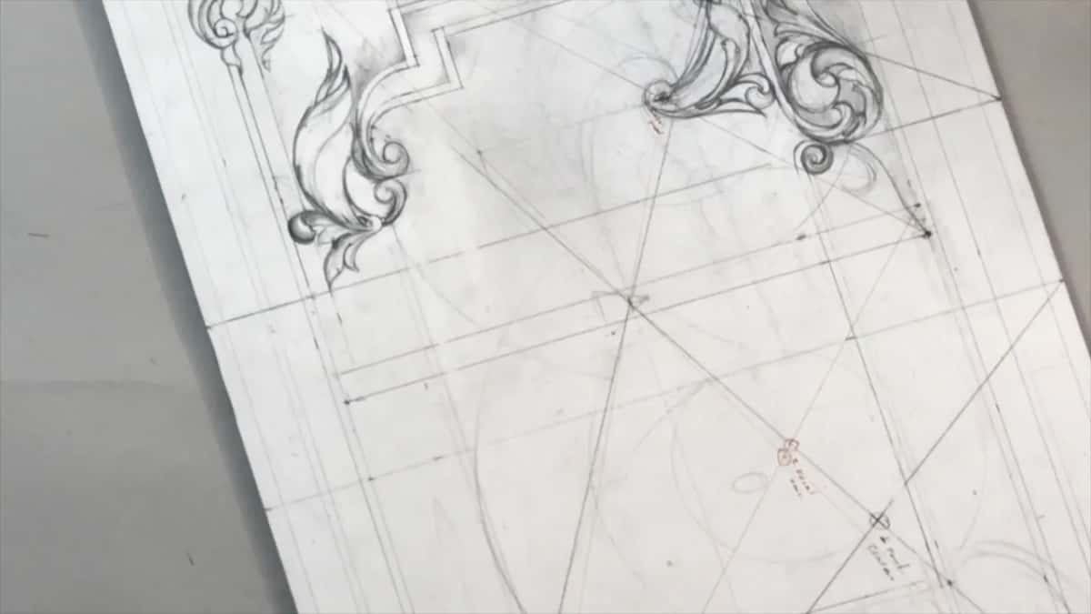 No hands in view, just the tilted sheet with a leaf and a scroll over the diagonals