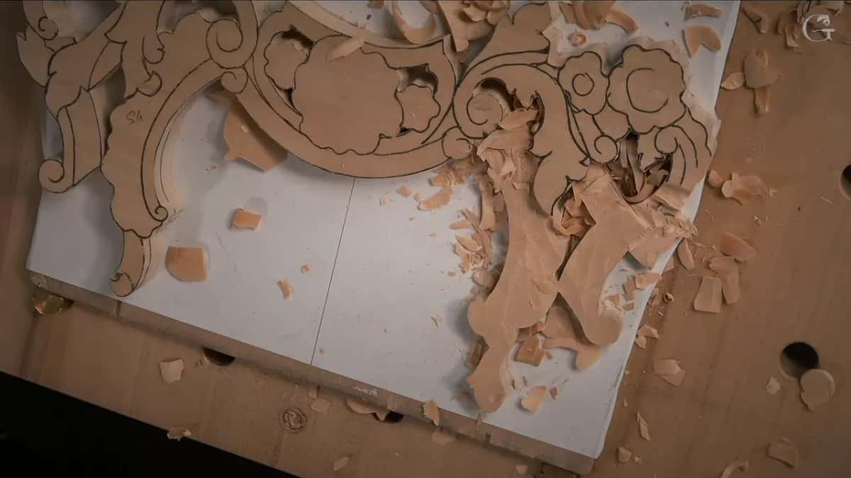 One half of the panel roughed out while the other half still waits untouched under its drawing, shavings heaped between them
