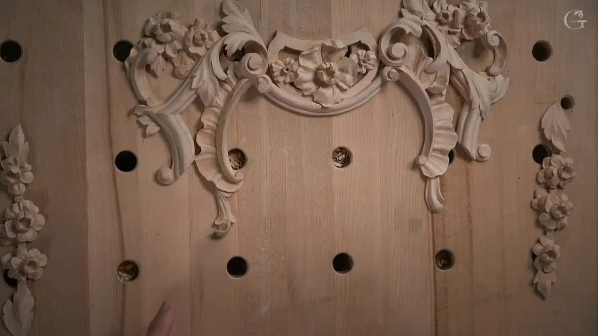 Finished carved composition laid out across the bench, rosettes and scrolls and flowers in their positions