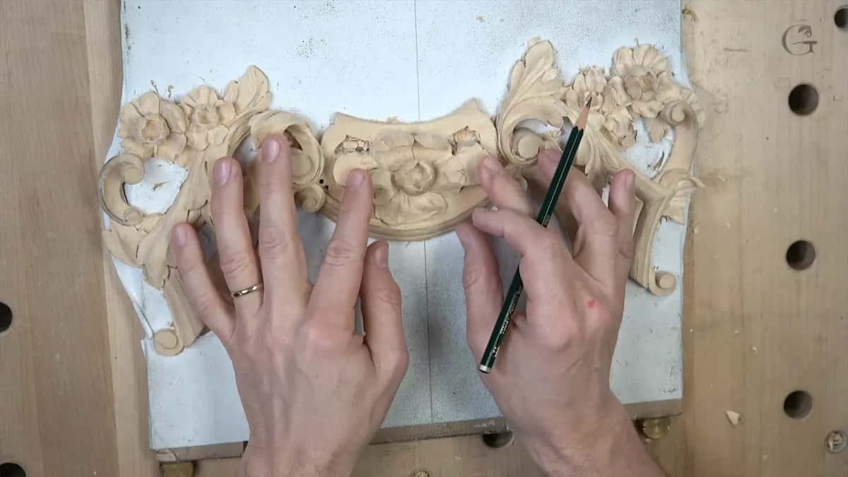 Both hands over the panel, a pencil laid across the flowers in the middle of it