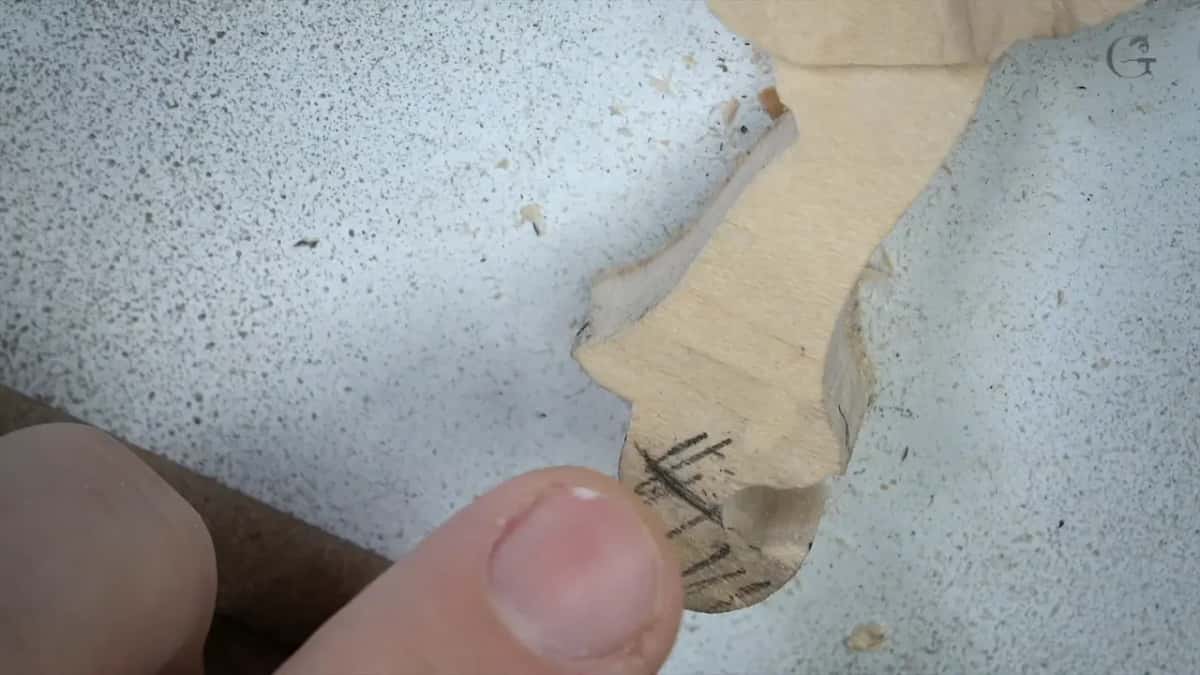 Close on the small detail, a thumb beside it, pencil marks still showing along its length