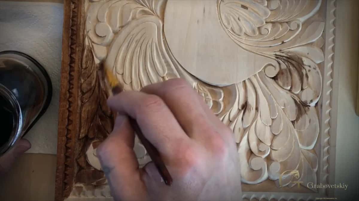 Brush working stain down into the carving, where no sanding means almost no grain will rise as it dries.