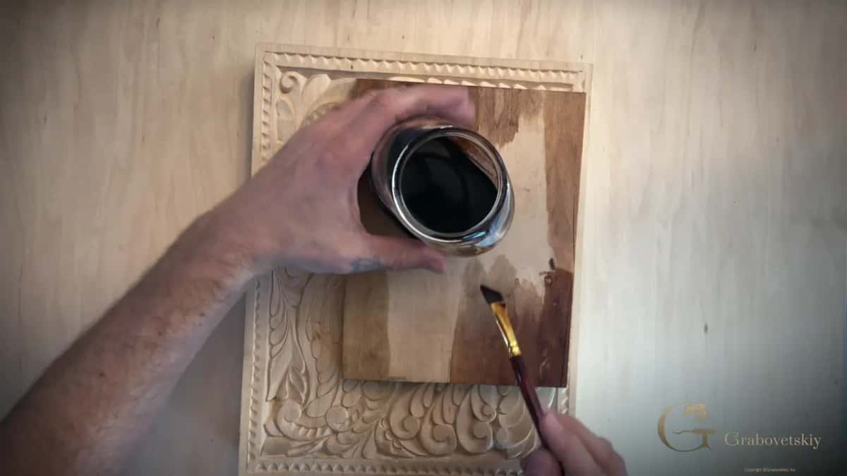 Testing the stain on a scrap of the same wood before any of it touches the carving itself.