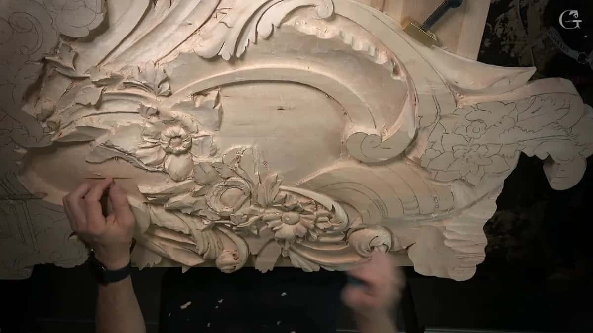 The carved panel from above, finished flowers and scrolls at left, pencil drawings of more flowers still waiting at right