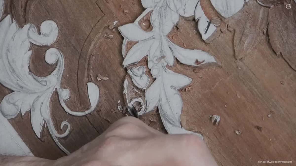 Carved scrollwork with the crossing shape outlined but nothing lowered yet, and a hand entering at the lower right.