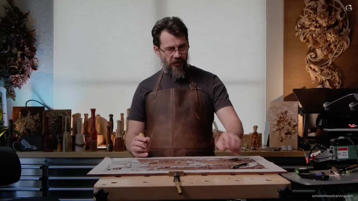 Alexander standing over the board in a leather apron, talking through a decision he has not made yet.