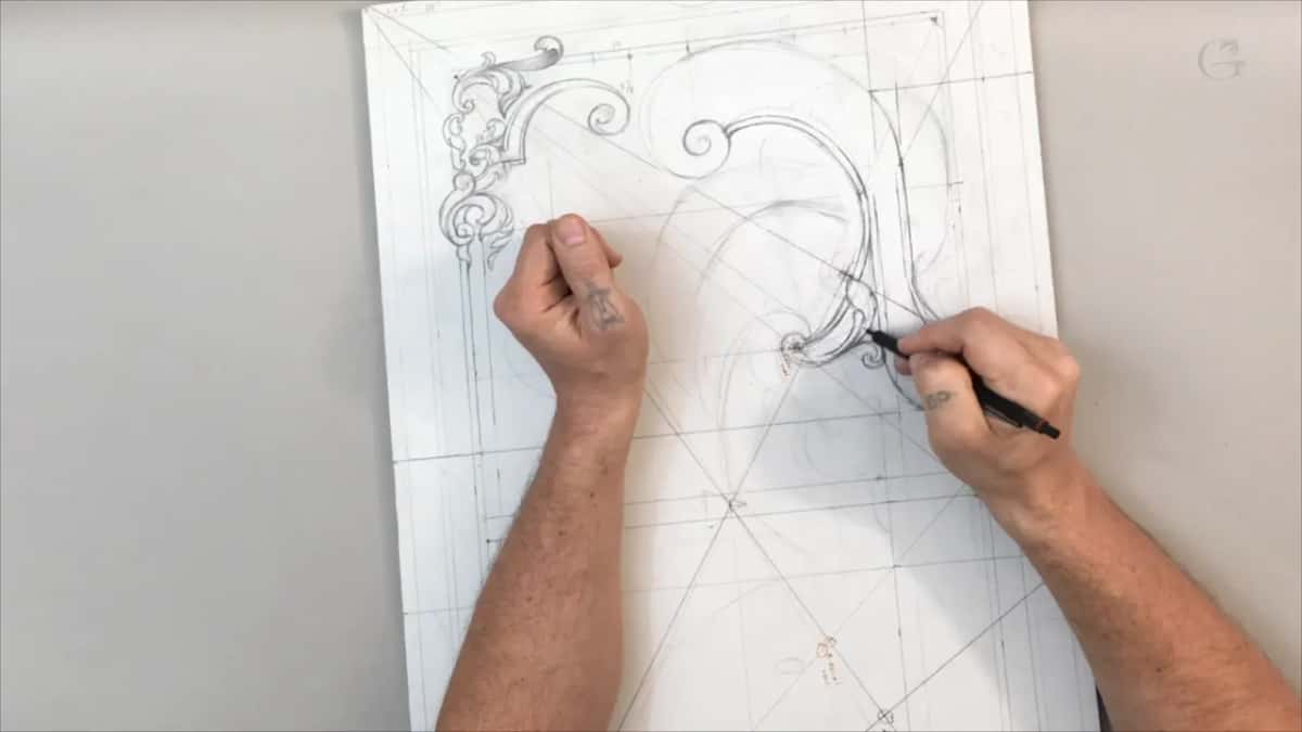 A fist resting at the top of the drawing while the pen works at the end of the scroll