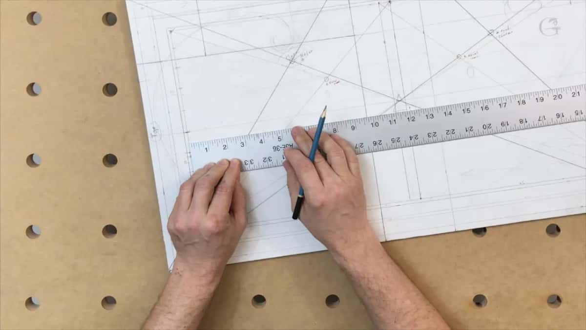 Rule laid flat across the lower bands, pencil set against its edge, paper crowded with layout lines