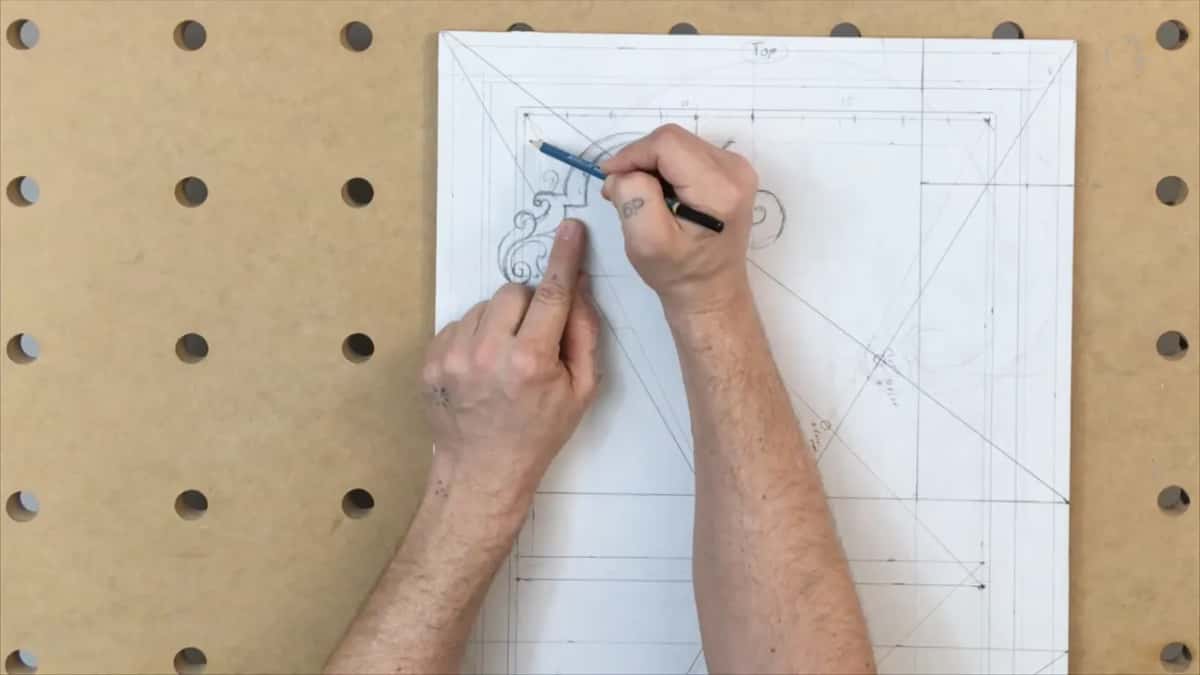 Wide view of the papered panel on the drilled board, one hand drawing near the top corner
