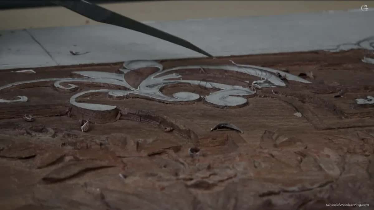 The carving at a low raking angle, the only way this dark timber shows any of its depth.