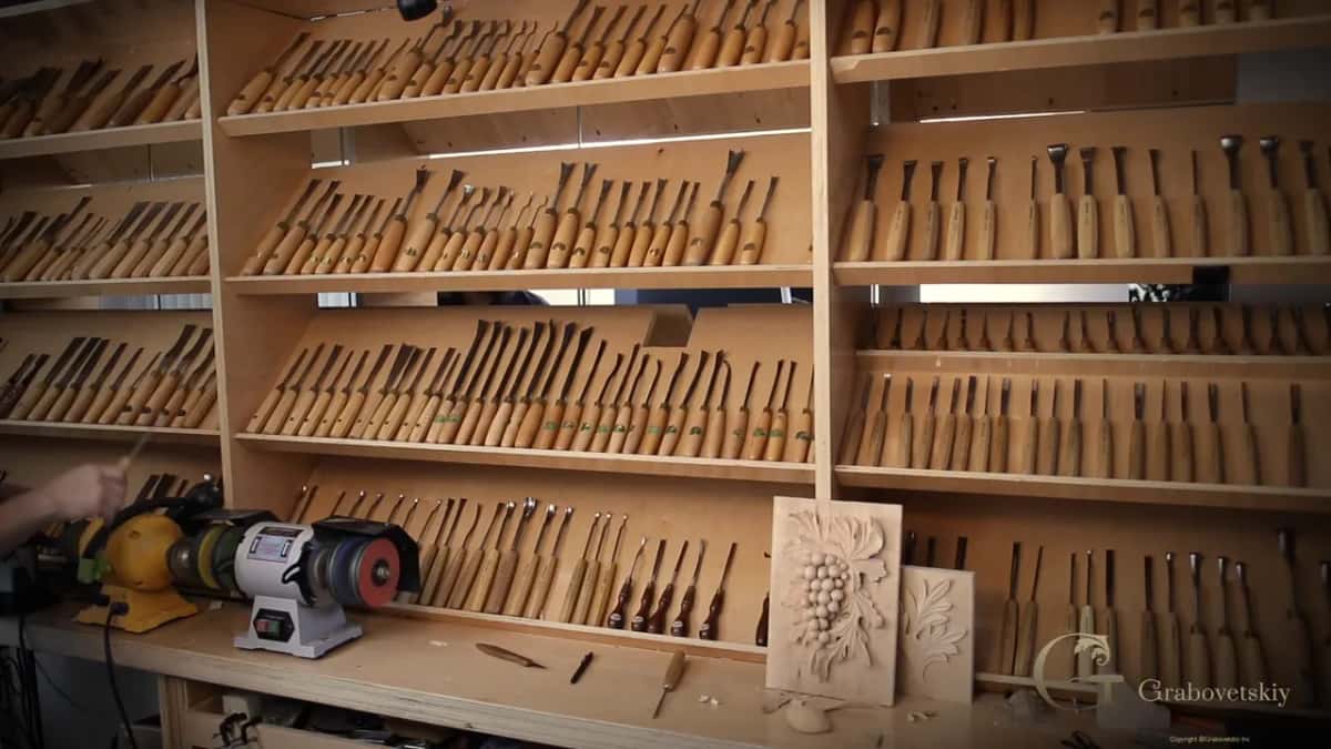 Shelves of gouges, grinders below, two carved panels