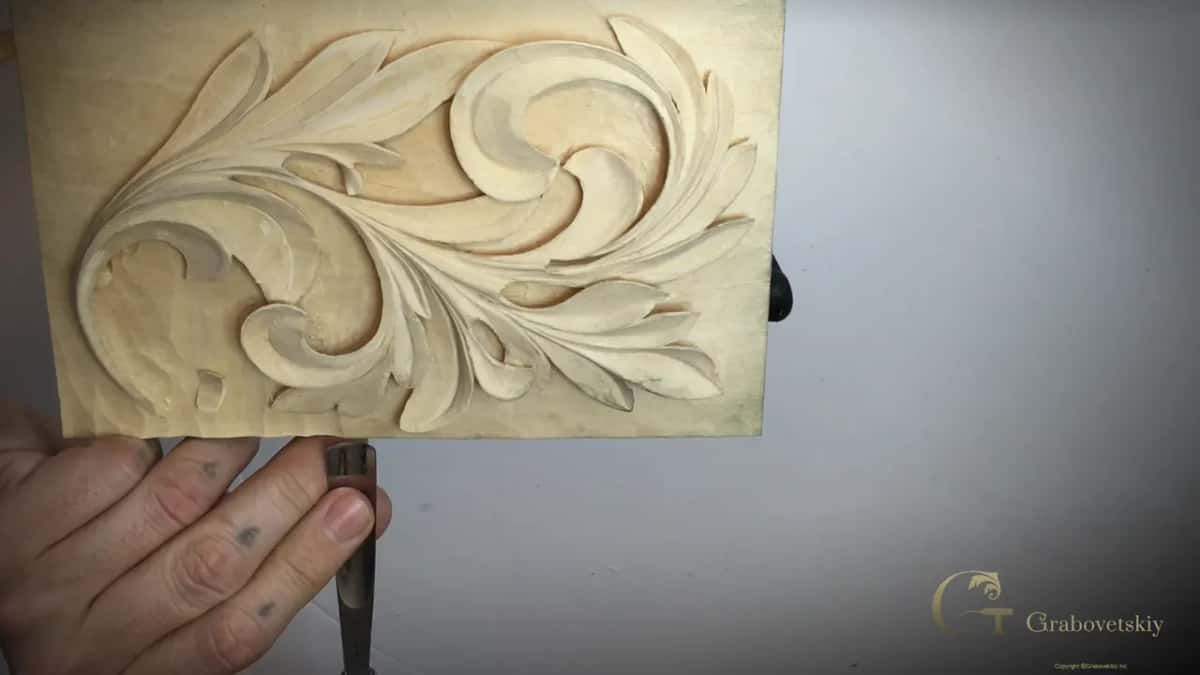 One hand under the upright board, a narrow tool at its lower edge