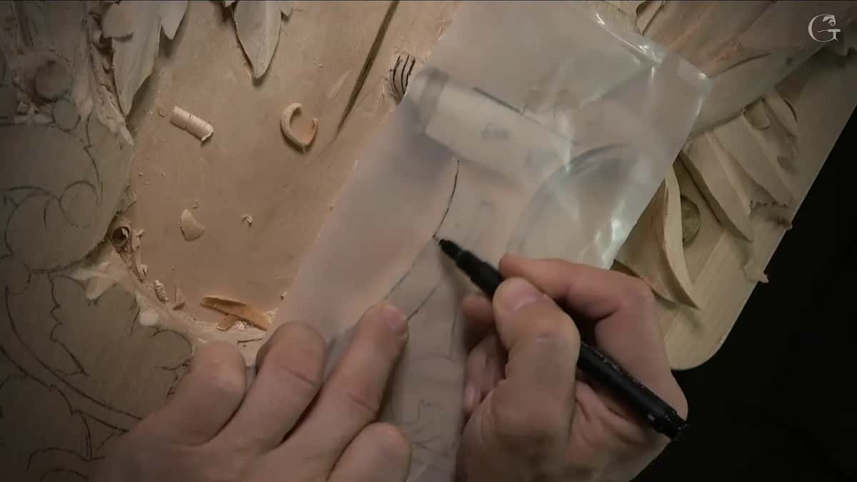 Clear plastic sheet over the carving while a black marker traces the lines through it