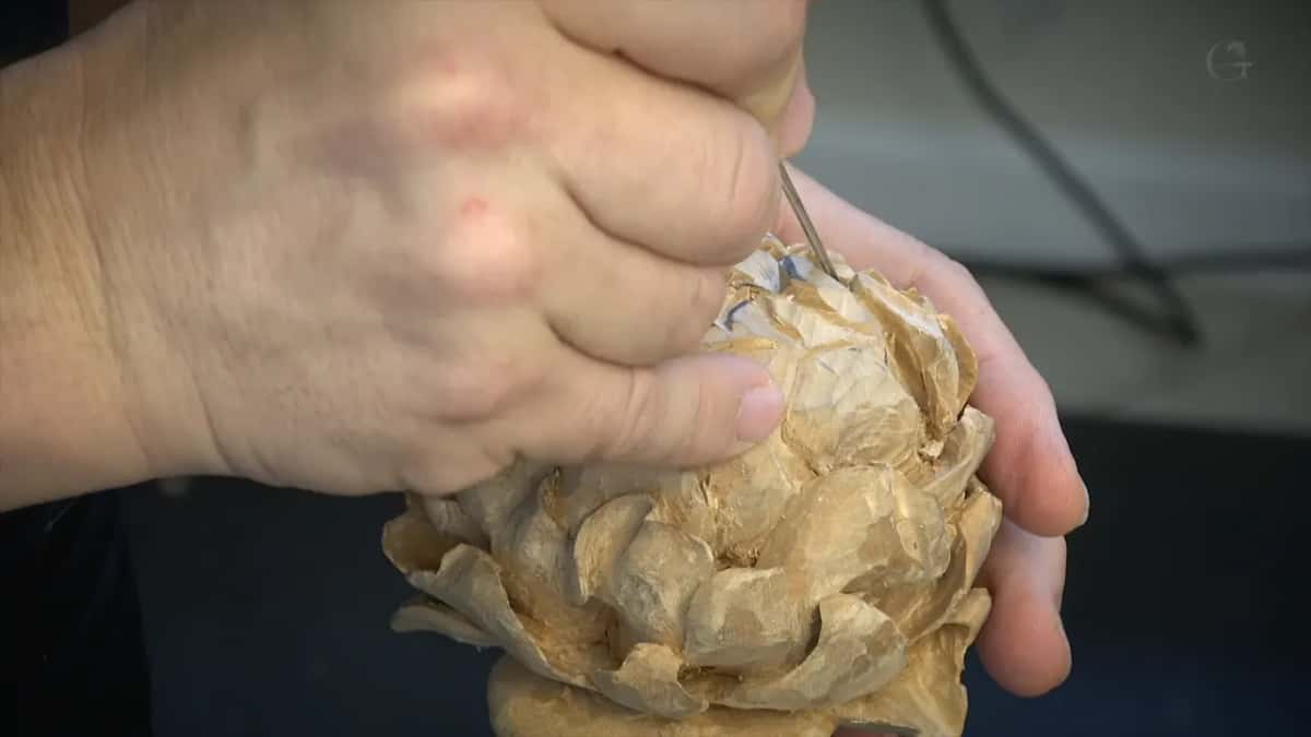 Both hands round the flower, a needle tool working the top of it.