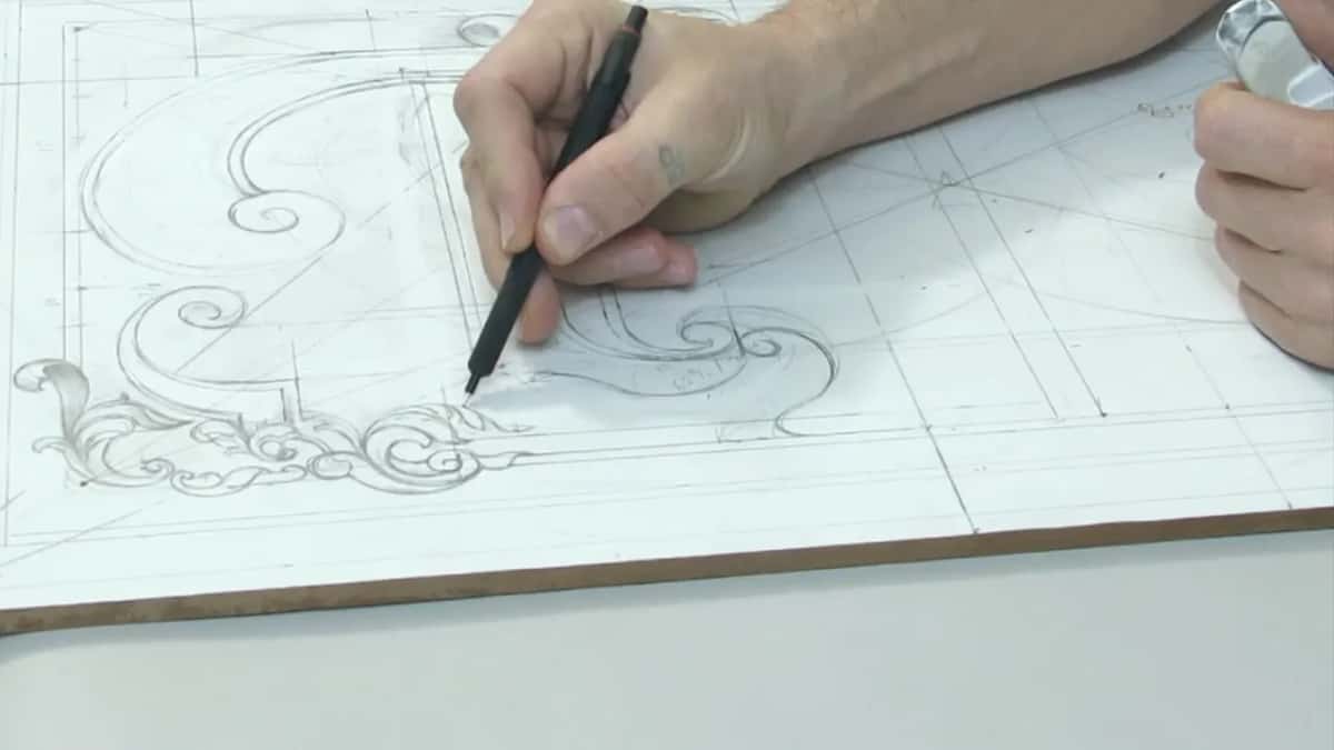 Seen low from the board edge, a pencil draws a scroll