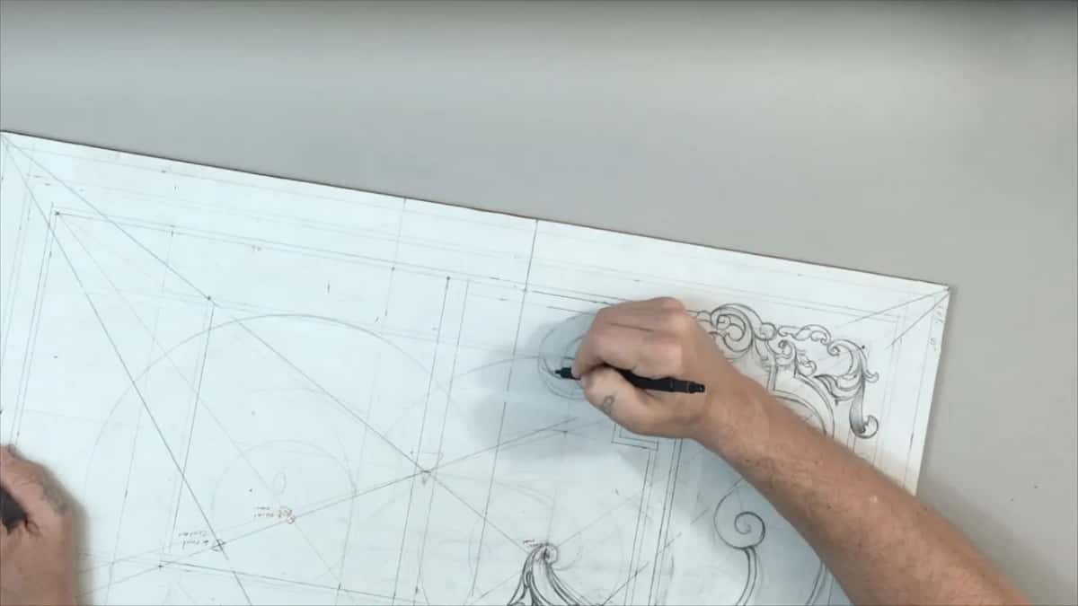Panel lying sideways at an angle, a black pencil drawing near the scrolls at its right end