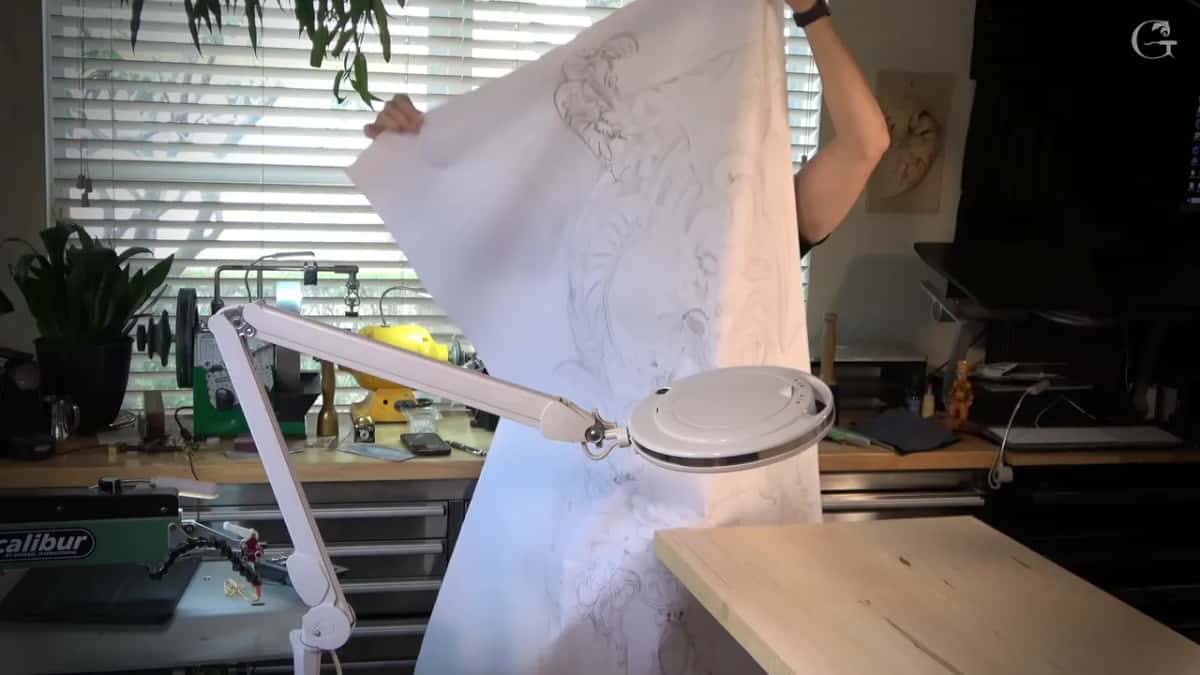 Printed pattern unrolled and held high, the drawing showing through the paper