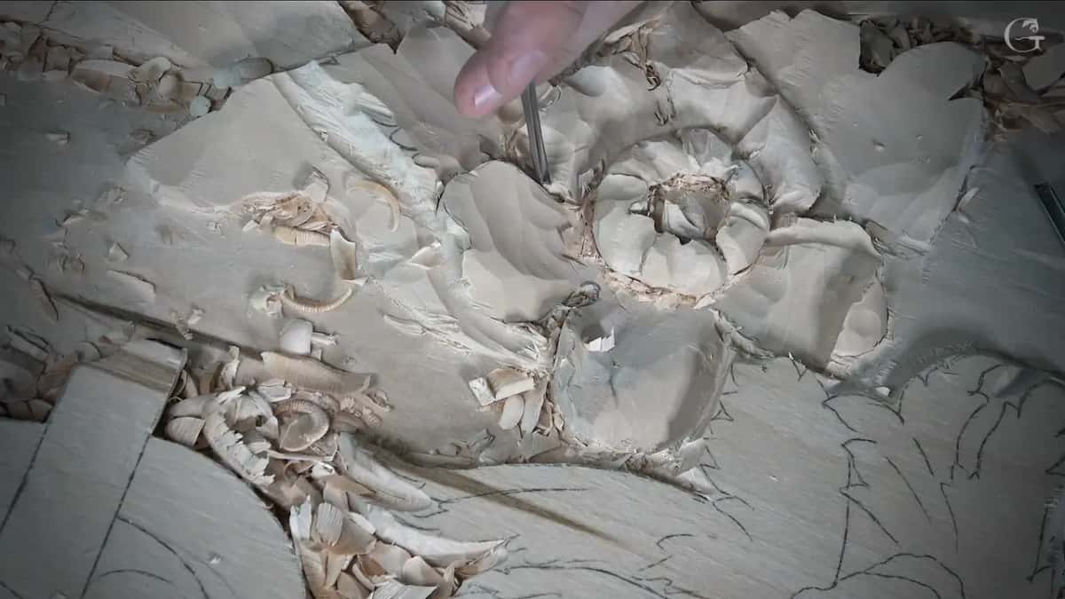 Fingertip steering a narrow tool into a pocket of the flower, close up, with shavings around it