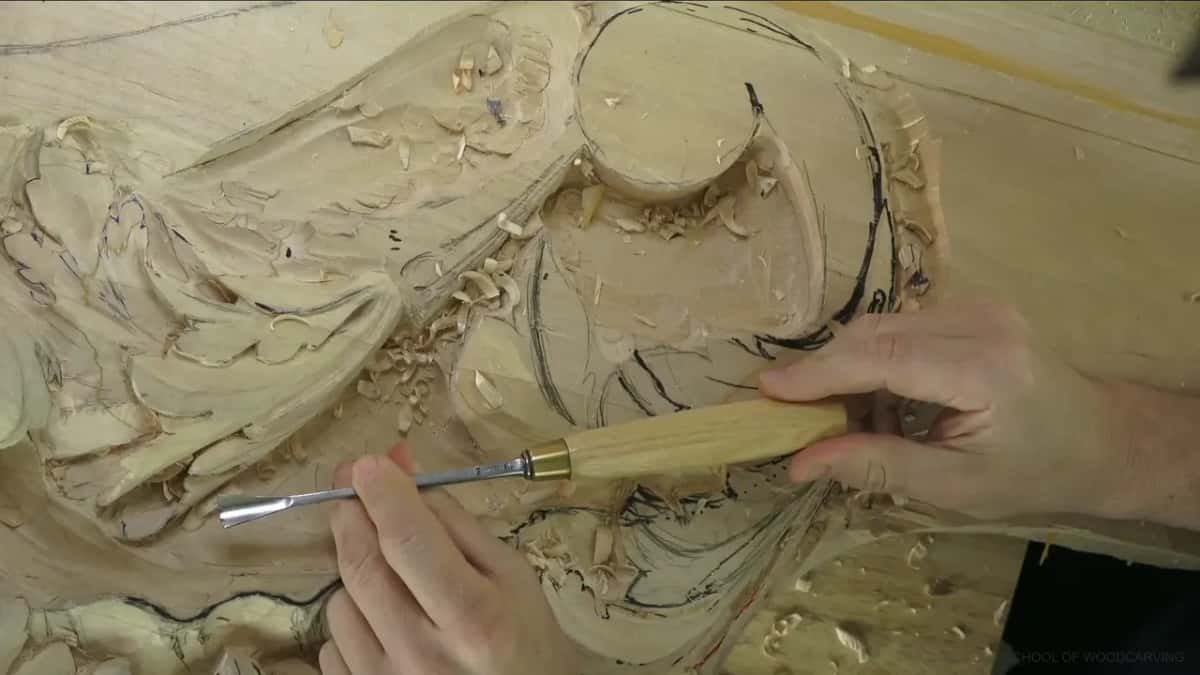 Long gouge with a brass ferrule across the scroll, one hand on the blade.