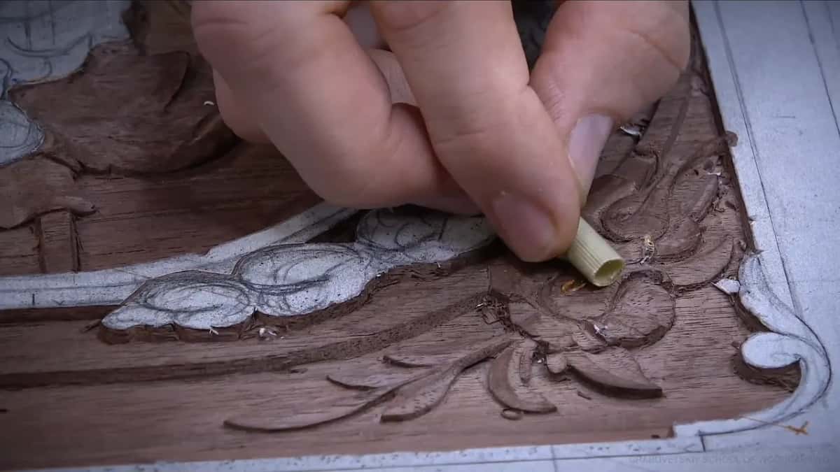 Hand pressing a hollow reed stem down onto the carved leaves