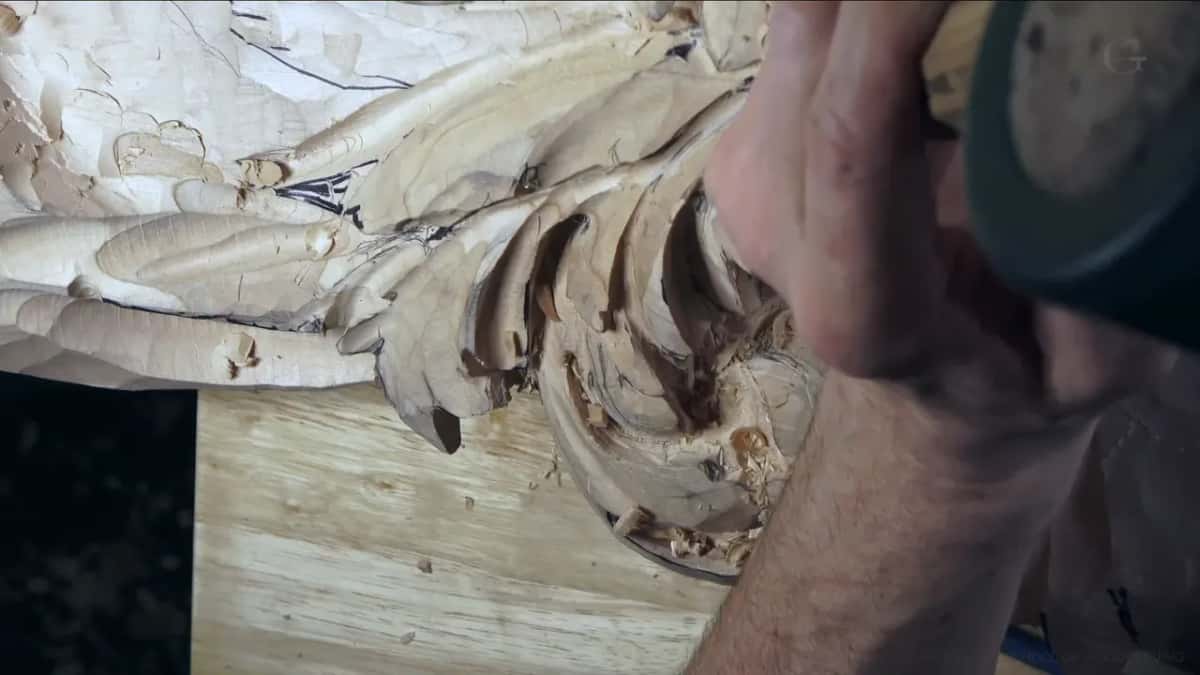 The round dark head of a mallet hangs above the hand.