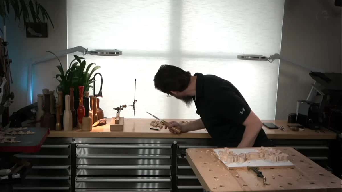 Bent low over the bench with a gouge in hand