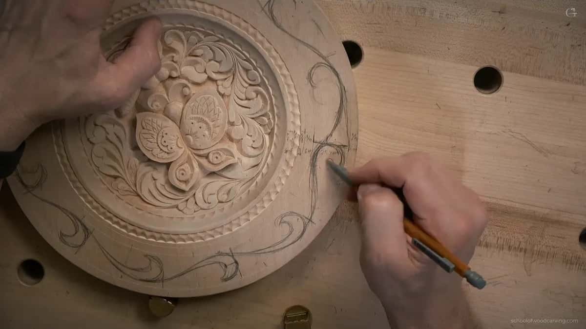 With the left hand spread on the plate, the other hand pencils leaf shapes along the right side
