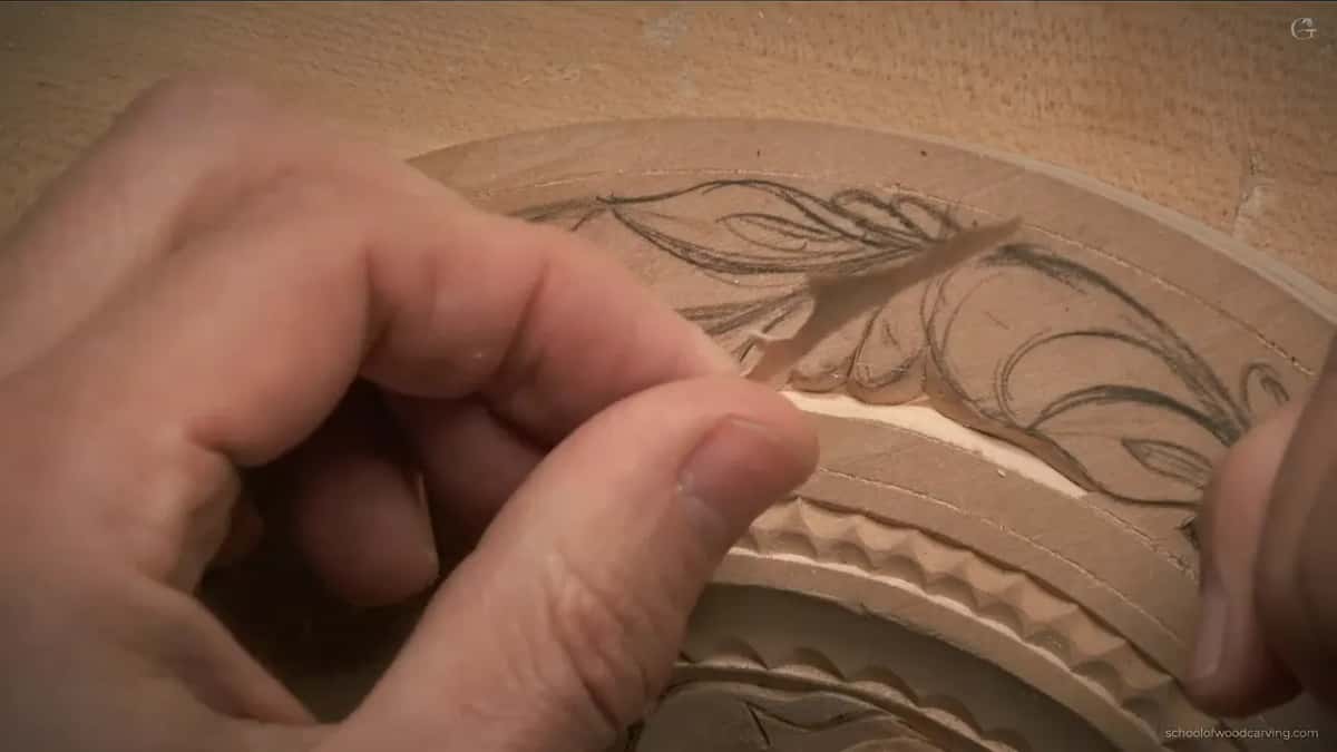 Thumb and forefinger pinch a thin curl of basswood that came loose from the fresh knife line