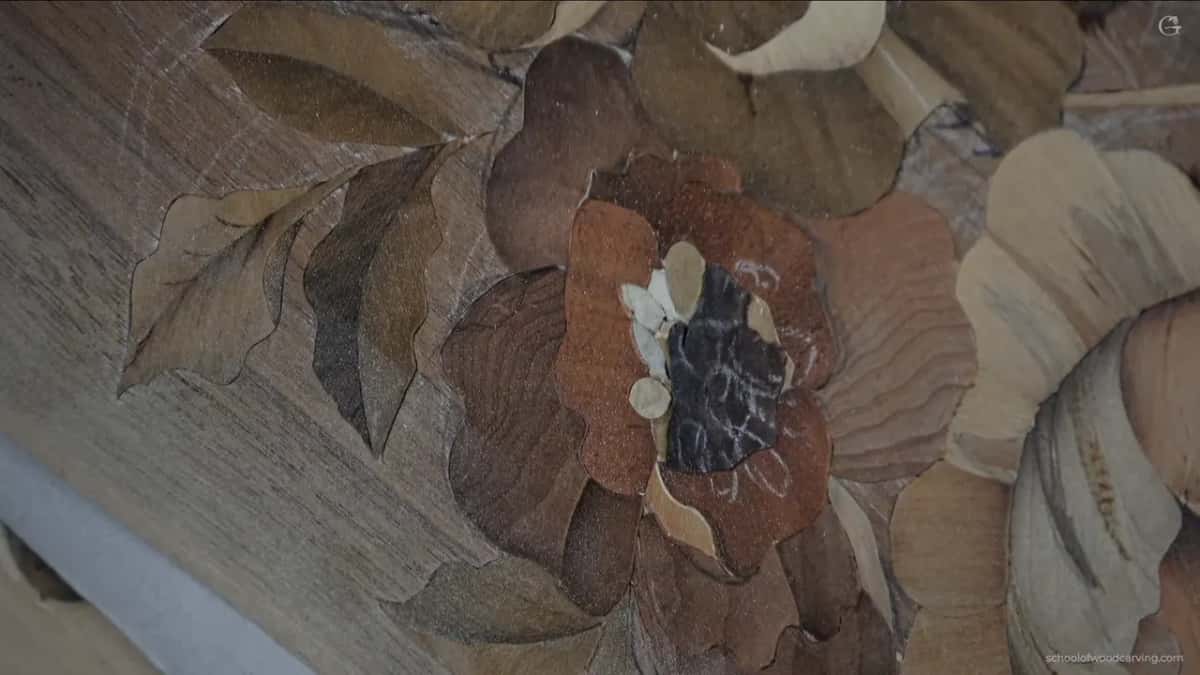 The same marquetry closer in, every petal cut so the figure in the timber runs the way the petal does.