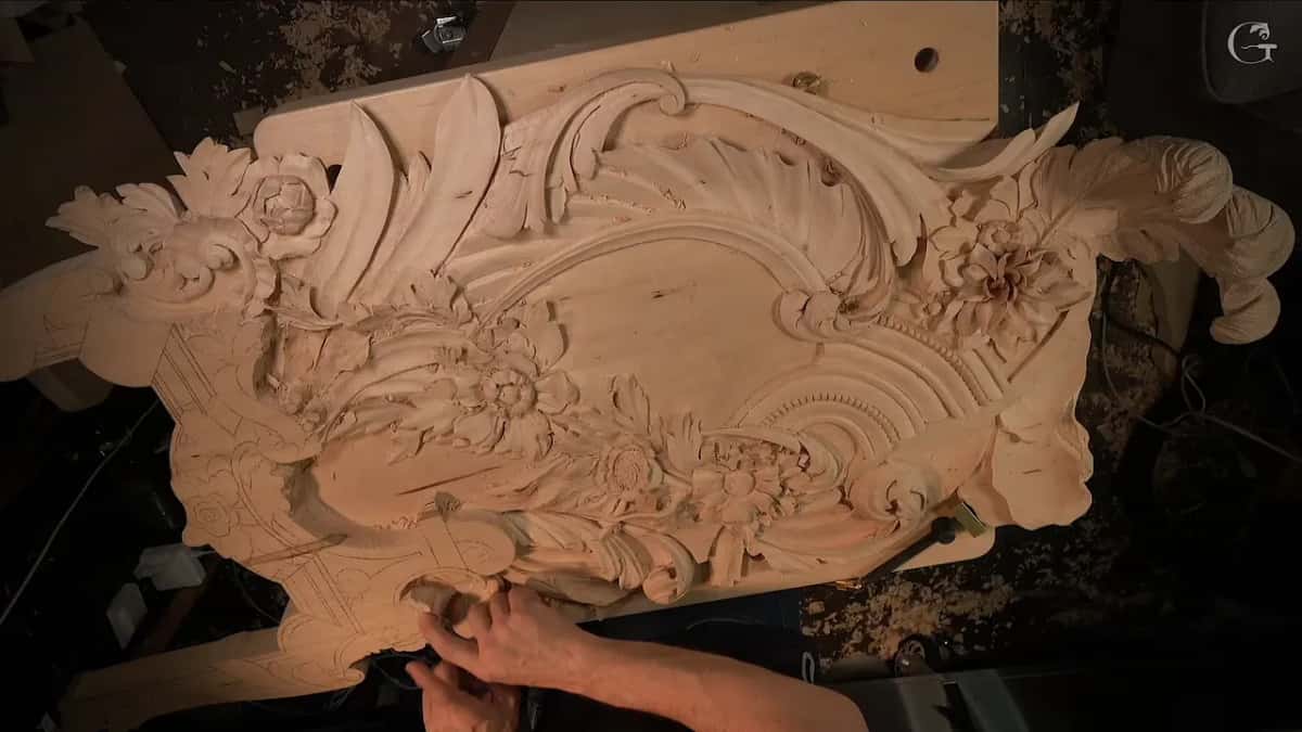 Fingers at the lower left edge, where pencil lines still cover the flat wood