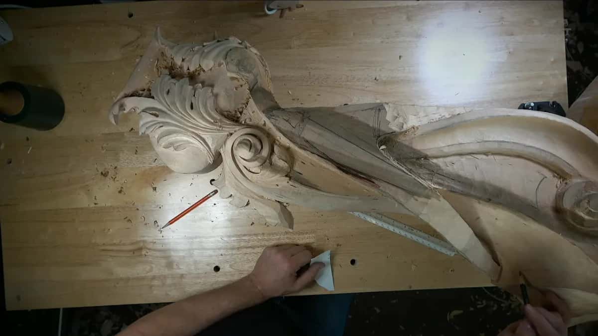 A small triangle of paper pressed flat on the bench while the other hand works at the edge